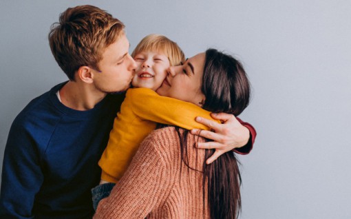 Una familia abrazándose: madre, padre e hijo sonriendo